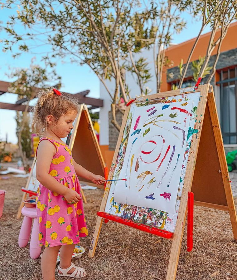 Menina a pintar num cavalete no espaço kids