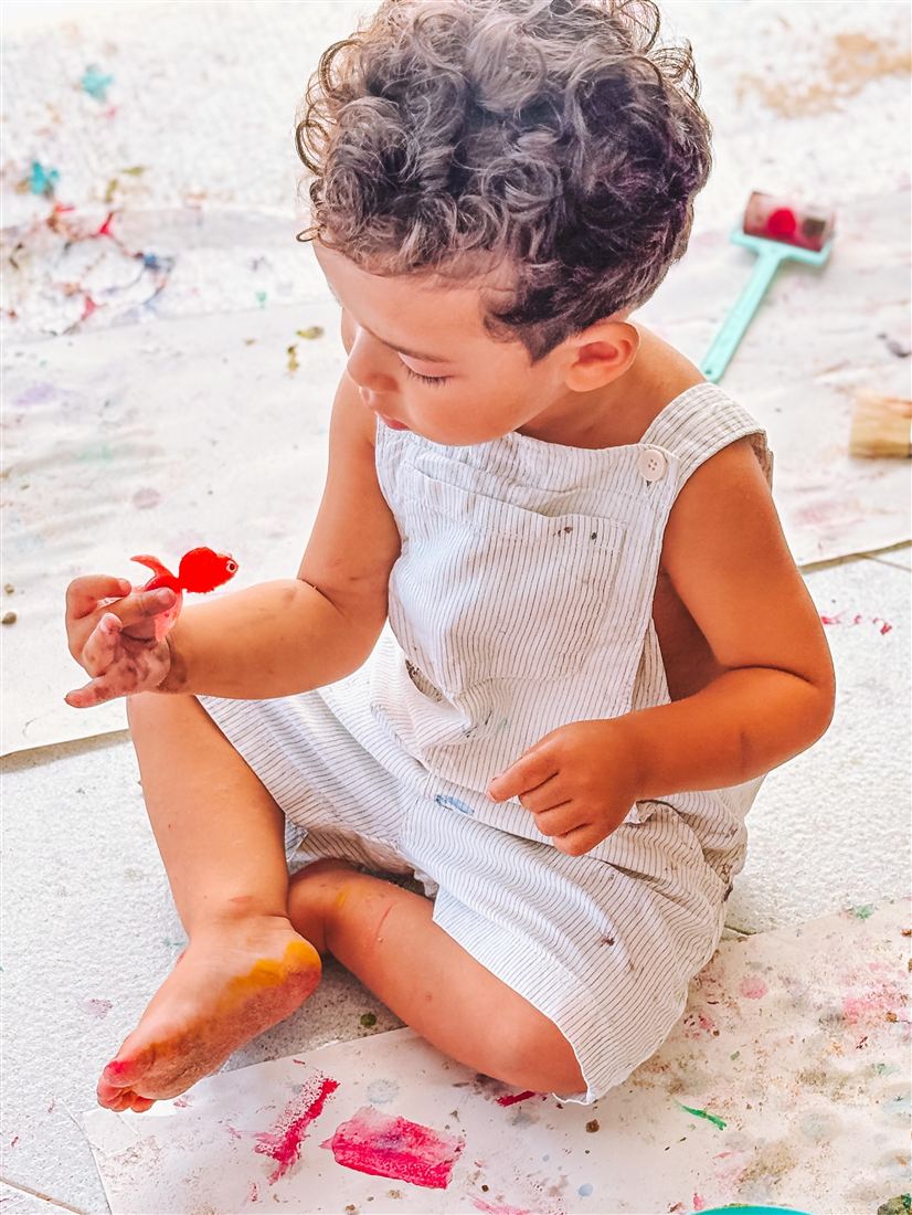 Bebé a explorar tinta no chão num ateliê de arte