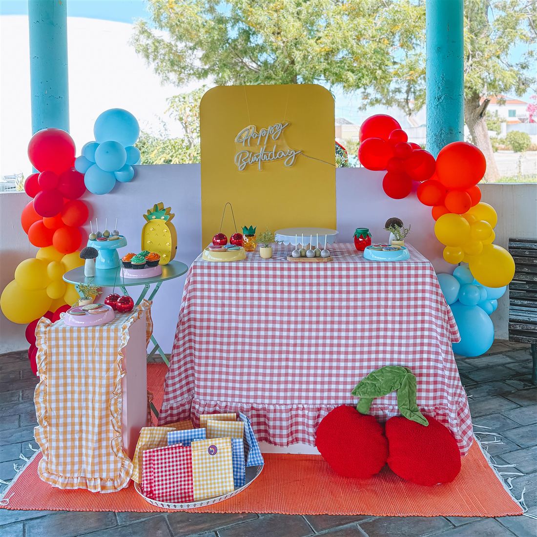 Mesa de festa com toalha aos quadrados e balões coloridos