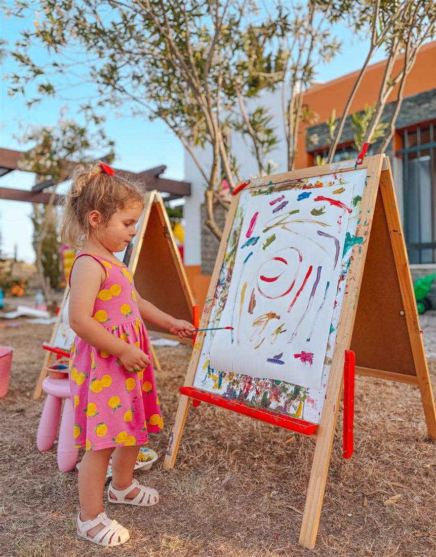 Menina a pintar num cavalete ao ar livre